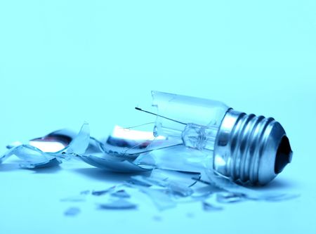 Broken lightbulb and it's fragments around on blue backgroundの写真素材