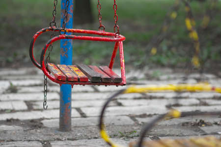 Old red swing on a playgroundの写真素材