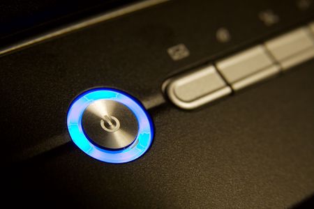 Closeup of a power button glowing in blueの写真素材