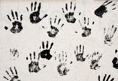 Handprints with black paint on white wallの写真素材