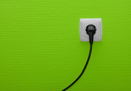 Electric outlet on green wall with cable pluggedの写真素材