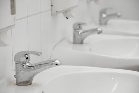 Taps in a row, white tilesの写真素材