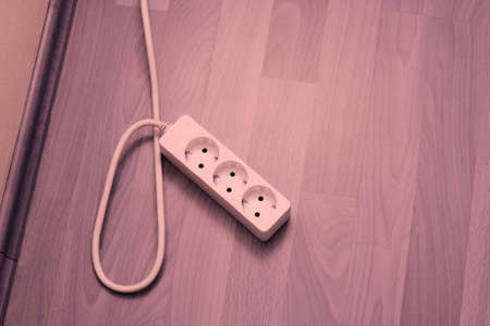 Plugged extension cable on parquet floorの写真素材