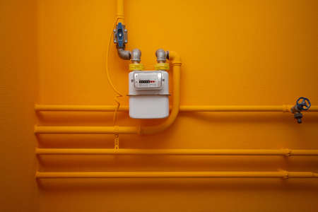 Pipes and gas-meter on orange wallの写真素材