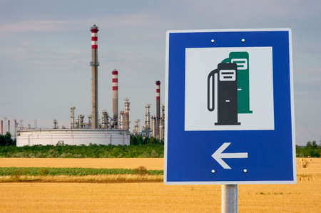 Fuel station sign in front of an oil refineryの写真素材