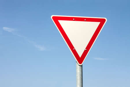 Give way traffic sign against clear blue skyの写真素材