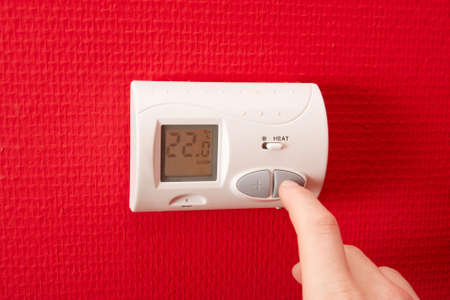 Adjusting the temperature on the thermostatの写真素材