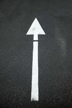 Arrow sign on asphalt surfaceの写真素材