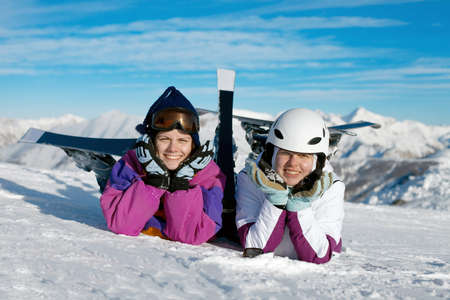 Happy female skiers resting in the snowの写真素材