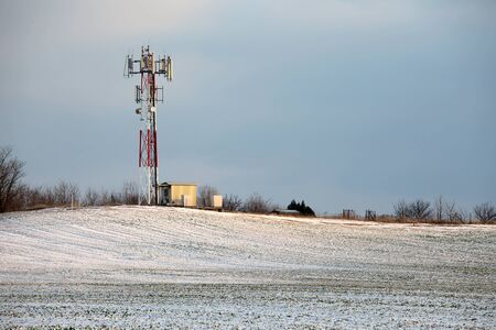 Telecommunication transmitter tower on a snowy fieldの写真素材