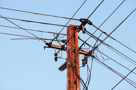 Old, rusty electric line against blue skyの写真素材