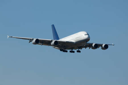 Airplane landing against clear blue skyの写真素材