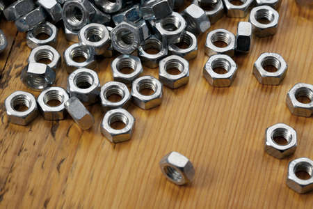 A pile of metal nuts on a wooden tableの写真素材