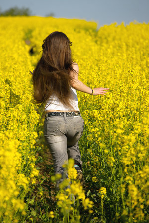 Girl running in the blooming rapeseed field