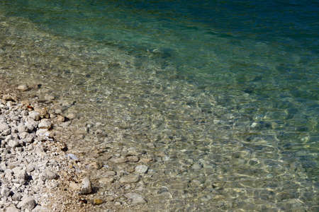 Calm water surface at a rocky shoreの写真素材