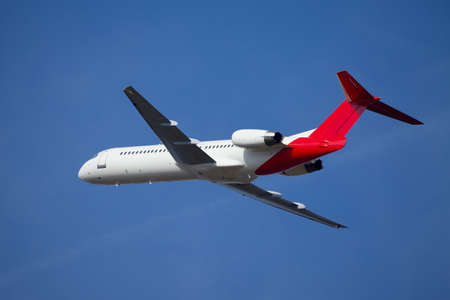 Airplane flying away to the blue skyの写真素材