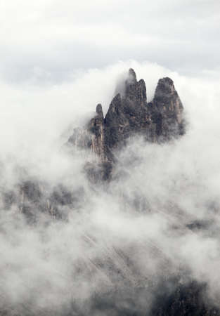 Mountain peak peeking through the clouds in the Dolomitesの写真素材