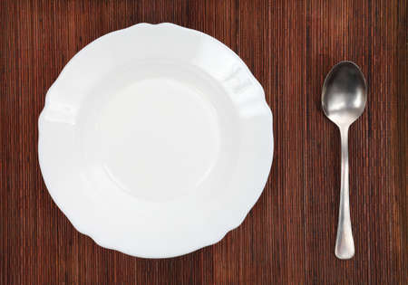 Empty plate and spoon on a tableの写真素材