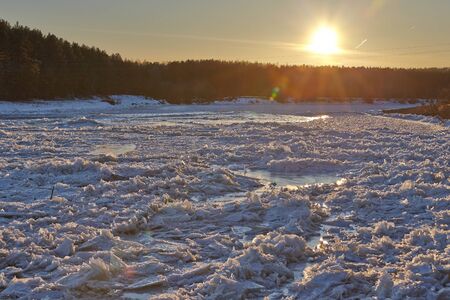 Frozen river with setting sunの写真素材