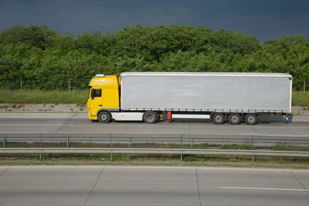 Yellow truck driving on the highwayの写真素材