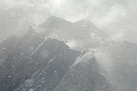 Heavy snowing, focused on the snowflakes, slightly blurry mountains in the backgroundの写真素材