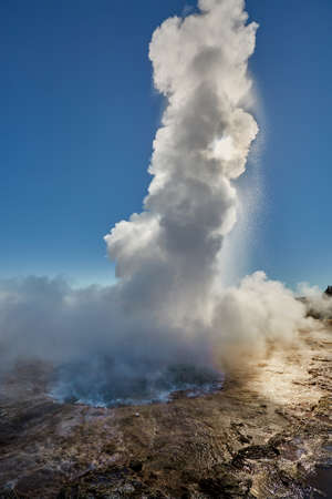 Erupting geyser in sunlightの写真素材