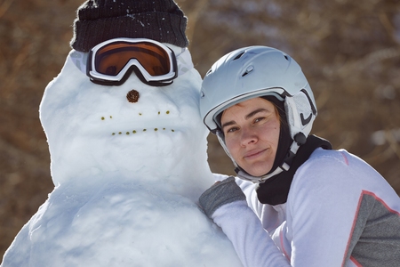 Skier posing with freshly made snowmanの写真素材