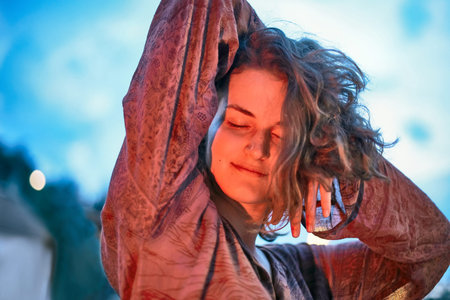 Young woman dancing in the light of fire at dusk