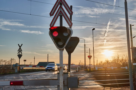 Red lights at a railway crossing, cars waiting for the train to pass