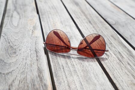 Sunglasses folded on a wooden tableの写真素材