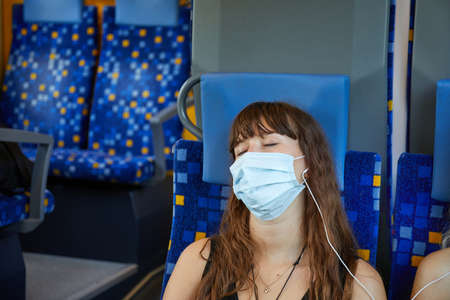 Young woman on a train wearing masksの写真素材