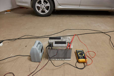 Charging a car starter battery in a garageの写真素材