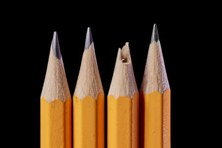 Pencil tips on black background, one brokenの写真素材