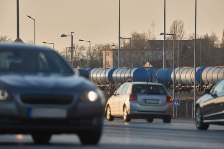 Road and rail transportation, oil freight wagons and cars passingの写真素材