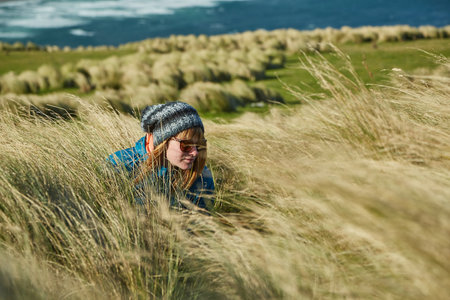 Woman squatting in tall grassの写真素材