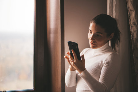 Cheerful girl in a white turtleneck talking at home on the phone. High quality photo