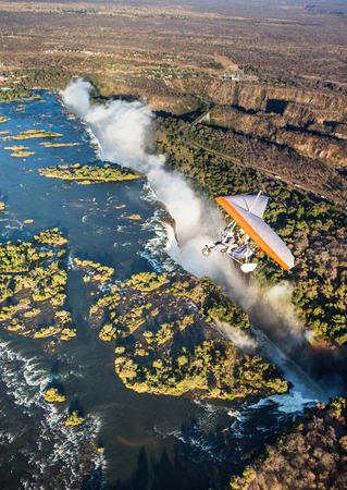 ZAMBIA, VICTORIA FALLS, AFRICA - 18 JULY: Tourists fly over the Victoria Falls on the trikes.のeditorial素材