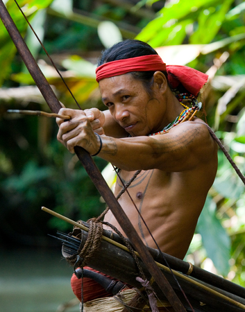 MENTAWAI PEOPLE, WEST SUMATRA, SIBERUT ISLAND, INDONESIA - 16 NOVEMBER 2010: Man hunter Mentawai tribe with a bow and arrow in the jungle.のeditorial素材