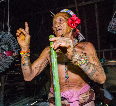 MENTAWAI PEOPLE, WEST SUMATRA, SIBERUT ISLAND, INDONESIA - 03 OKTOBER 2011: Mentawai tribe man sitting at home.のeditorial素材