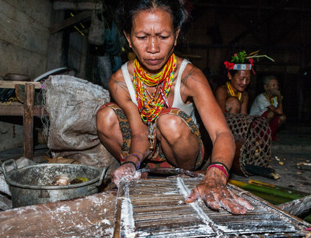 MENTAWAI PEOPLE, WEST SUMATRA, SIBERUT ISLAND, INDONESIA - 03 OKTOBER 2011: Mentawai tribe woman sitting in a traditional house on the floor.のeditorial素材