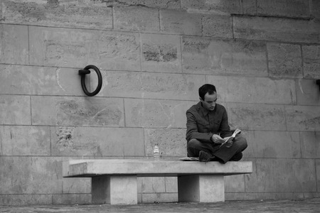 PARIS, FRANCE - AUGUST 12, 2006: A man sitting on a bench on the waterfront of the River Seine and reading a book.のeditorial素材