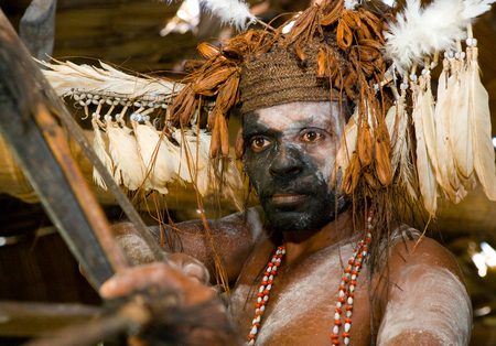 INDONESIA, IRIAN JAYA, ASMAT PROVINCE, JOW VILLAGE - JUNE 12: Warrior Asmat tribe is sitting at home in traditional headdress and war paint.のeditorial素材
