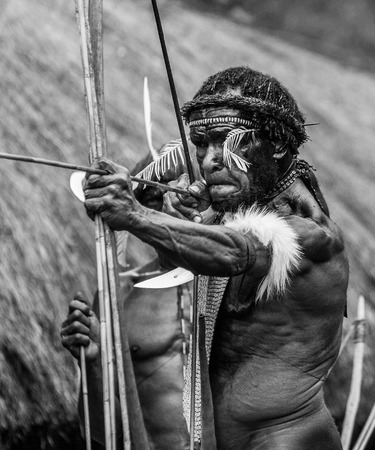 DANI VILLAGE, WAMENA, IRIAN JAYA, NEW GUINEA, INDONESIA - 15 MAY 2012: Men Dani tribe shoot an arrow.のeditorial素材