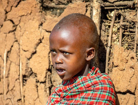 Masai child on the background of the wall of a traditional clay village house. Tanzania, East Africa, August 12, 2018.のeditorial素材