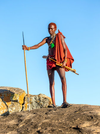 ANZANIA, EAST AFRICA - AUGUST 12, 2018: Young Masai warrior is standing on a big stone in...