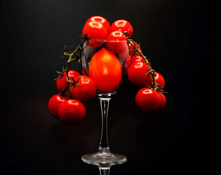 Composition of tomatoes of different sizes and colors in a wine glass. Natural product. Natural color. Close-up.の写真素材