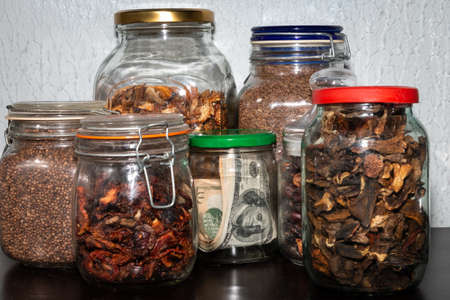 Dollars in a glass jar, among other jars of cereals and dried fruits. financial stock.の写真素材