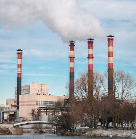 Factory chimneys release clouds of smoke into the sky against a blue sky. The concept of air pollution, environment, industry and ecology, global warming.の写真素材