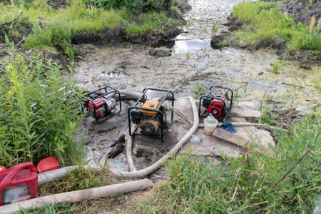 Water pumps pump water from the pond. Drainage of a reservoir, swamp, lake with the help of high pressure water pumps.の写真素材