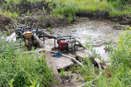 Drainage of a reservoir, swamp, lake with the help of high pressure water pumps. Water pumps pump water from the pond. Drainage of swamps reduces the feeding of small and large rivers.の写真素材
